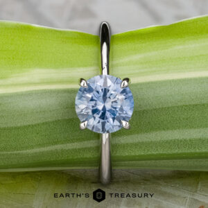 The "Tiara" ring in platinum features a 2.00-carat Montana sapphire, showcased atop a green leaf with "Earth's Treasury" displayed below.
