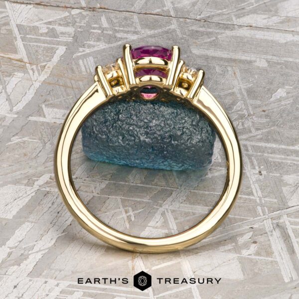 The "Dryope" ring in 18k yellow gold with 1.41-Carat Ceylon sapphire The "Dryope" ring in 18k yellow gold showcases a 1.41-carat Ceylon sapphire flanked by two diamonds, displayed upright on textured blue stone with the Earth's Treasury logo below. Inspired by the enchanting Dryope collection.
