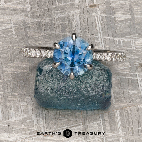 The Pave "Anemone" ring in 14k white gold with 1.82-carat Montana sapphire The Pave "Anemone" ring in 14k white gold with a 1.82-carat Montana sapphire is displayed on rough blue stone over a textured gray surface, highlighting its stunning design and exceptional jewelry craftsmanship.