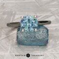 The "Cathedral" ring in platinum features a 2.16-carat Montana sapphire and is shown atop a rough blue crystal with the text "Earth's Treasury" below.