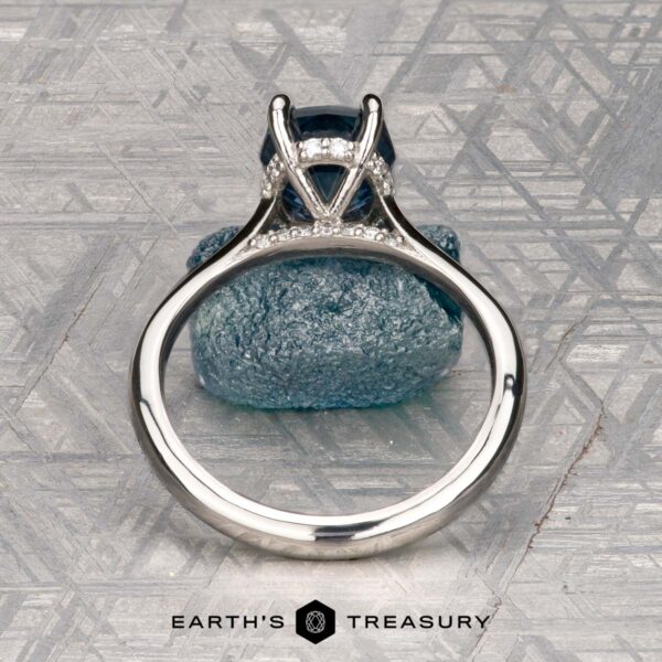 The "Anastasia" ring in platinum with 2.34-carat Montana sapphire The "Anastasia" ring in platinum, featuring a 2.34-carat Montana sapphire and hidden halo diamonds, stands upright on a textured gray surface. The EARTH'S TREASURY logo and text are displayed at the bottom.