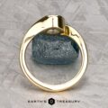 The "Calliste" ring in 18K yellow gold with a 1.08-carat Montana sapphire is shown upright on a gray textured surface, with the "Earth's Treasury" logo and text at the bottom.