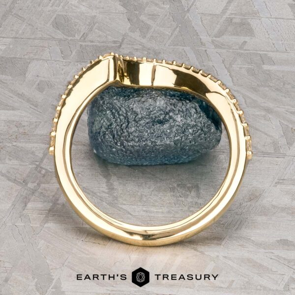 The "Calliste" band in 18K yellow gold The "Calliste" band in 18K yellow gold stands upright on a gray stone atop a patterned metallic surface, with the Earth’s Treasury logo displayed below.