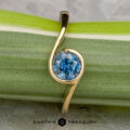 The "Calliste" ring in 18K yellow gold with a 1.08-carat Montana sapphire from Calliste Jewelry is shown on a green and white striped plant stem, with the "EARTH'S TREASURY" logo at the bottom.