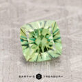 A 1.63-carat Demantoid Garnet, with square cuts and reflective facets, sits on a textured gray surface.
