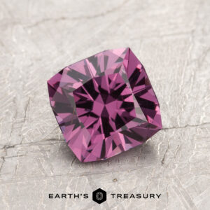 The ET1993, a square-cut purple gemstone with intricate facets, is elegantly displayed on a textured gray surface.