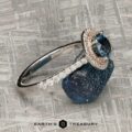 The "Victoria" Ring in 14k rose and white gold with a 1.05-carat Montana sapphire and white accent stones rests on a rough blue mineral; Earth's Treasury logo appears below.