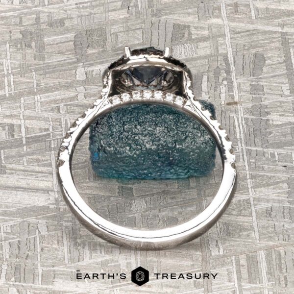 The "Victoria" Ring in 14k rose and white gold with 1.05-Carat Montana Sapphire The "Victoria" Ring in 14k rose and white gold features a 1.05-carat Montana sapphire as the center stone, accented by small clear stones along the band. Displayed on a rough blue crystal with the "EARTH'S TREASURY" logo at the bottom.