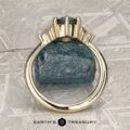 The “Mari” ring in 14k yellow gold with a 1.63-carat Montana Sapphire is shown on a rough blue stone, with the "Earth's Treasury" logo and text at the bottom.