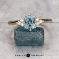 The "Mari" ring in 14K yellow gold with a 1.23-carat Montana sapphire is displayed on a rough blue crystal, with Earth's Treasury's logo below.