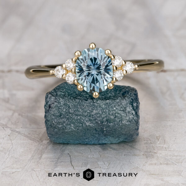 The "Mari" ring in 14K yellow gold with 1.23-carat Montana sapphire The "Mari" ring in 14K yellow gold with a 1.23-carat Montana sapphire is displayed on a rough blue crystal, with Earth's Treasury's logo below.