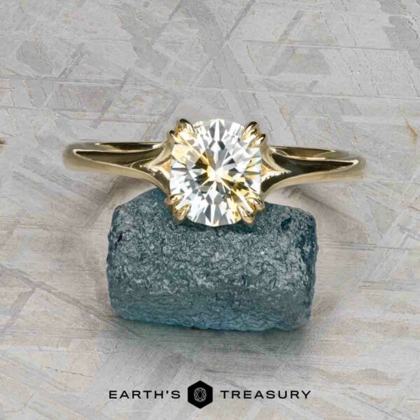 The "Daphne" ring in 14k yellow gold with 1.71-carat Montana sapphire The "Daphne" ring in 14k yellow gold with a 1.71-carat Montana sapphire rests on a rough blue stone over a gray textured surface. The text "EARTH'S TREASURY" below captures the elegance of Daphne's timeless style.