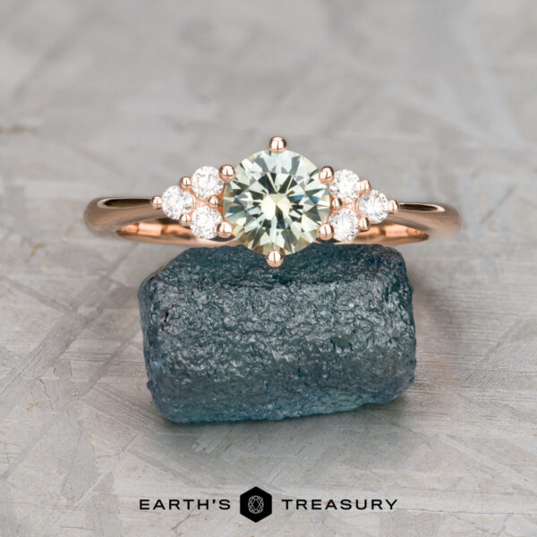 The "Mari" ring in 14k rose gold with 0.81-carat Montana sapphire The "Mari" ring in 14k rose gold with a 0.81-carat Montana sapphire is displayed on a rough blue stone, small diamonds accenting the band, with the "Earth's Treasury" logo below.