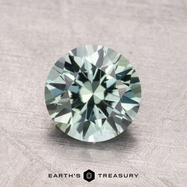 1.77-Carat Mint Green Montana Sapphire (Heated) A 1.77-carat heated mint green sapphire from Montana is placed on a textured surface, labeled "Earth's Treasury.