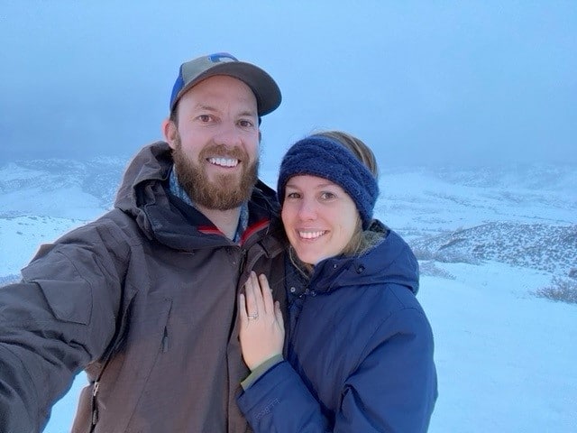 A photo from a customer review of a couple in the snow showing off their new engagement ring