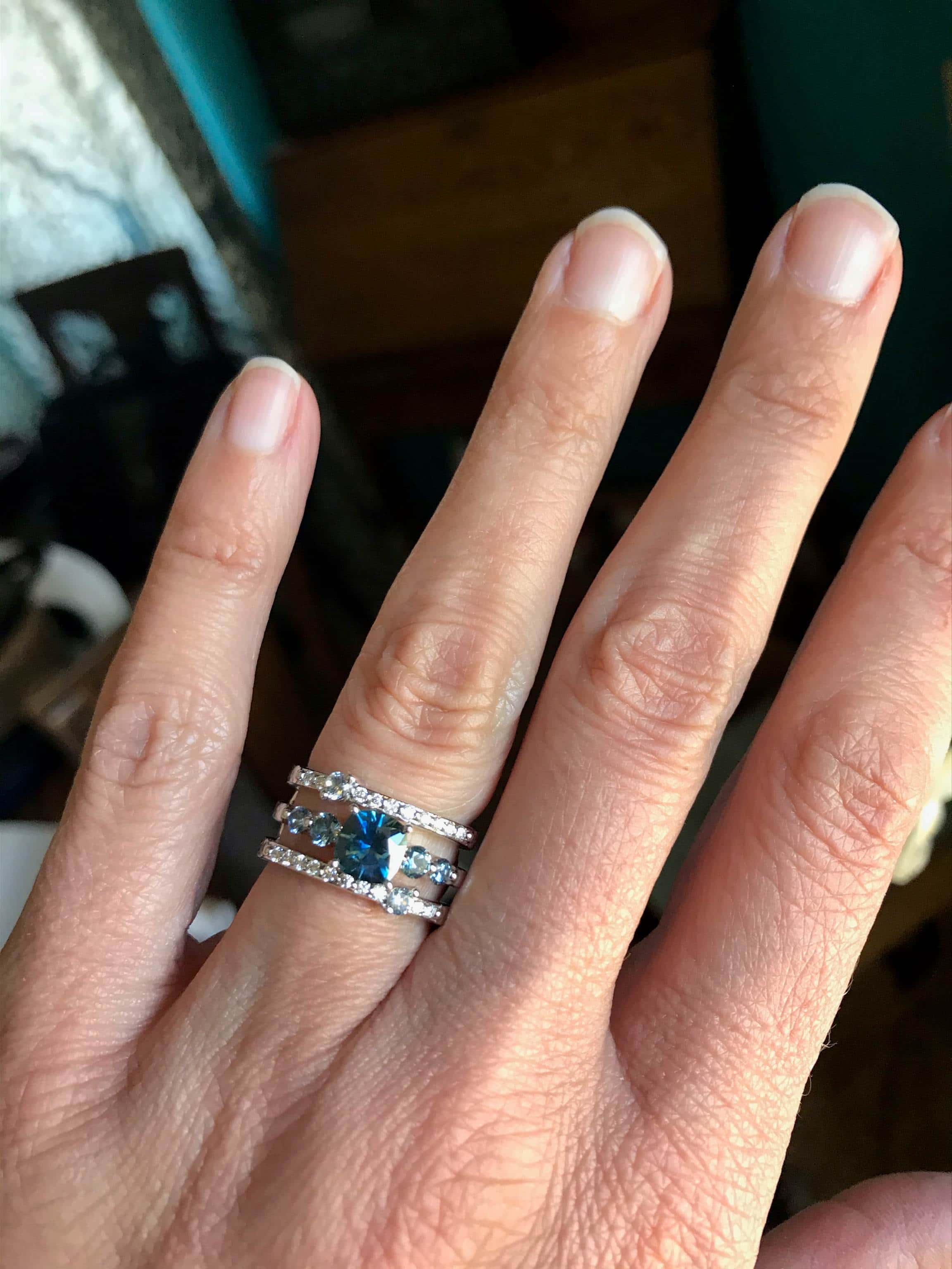 A photo from a customer review featuring a "Lamia" ring in 14k white gold with 1.12-Carat Montana Sapphire, alongside a custom double-band jacket