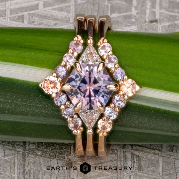 The "Melilai" Ring in 20k Pink Gold with 1.42-carat Montana sapphire, alongside the "Melilai" band in 20k pink gold The "Melilai" Ring in 20k pink gold with a 1.42-carat Montana sapphire, paired with the "Melilai" band, elegantly rests on a green plant stem.