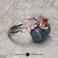 The "Dahlia" ring is crafted in platinum and set with a 2.14-carat Montana sapphire, showcased on a gray textured surface.