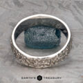 The "Luna" band in platinum, 6mm, features a textured design encircling a rough blue gemstone, shown on a gray patterned surface with the Earth's Treasury logo below.