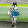 Stacked from 51 images. Method=B (R=1,S=4)" is a stunning silver Halley ring with a round blue gemstone and two clear stones, showcased on green with the "Earth's Treasury" logo below.