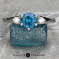 A "Stacked from 52 images. Method=B (R=1,S=4)" silver Halley Ring with a blue gemstone center and two clear side stones is shown on rough blue crystal, with "Earth's Treasury" text at the bottom.