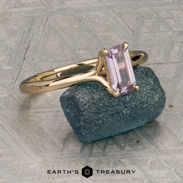 The "Phoebe" ring in 14K yellow gold with 0.73-carat Montana sapphire The "Phoebe" ring in 14K yellow gold, featuring a 0.73-carat Montana sapphire, is displayed on a rough blue stone atop a textured gray surface with the text "Earth's Treasury" below.