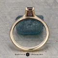 The "Phoebe" ring in 14K yellow gold, featuring a 0.73-carat Montana sapphire, is displayed on a rough blue stone atop a textured gray surface with the text "Earth's Treasury" below.