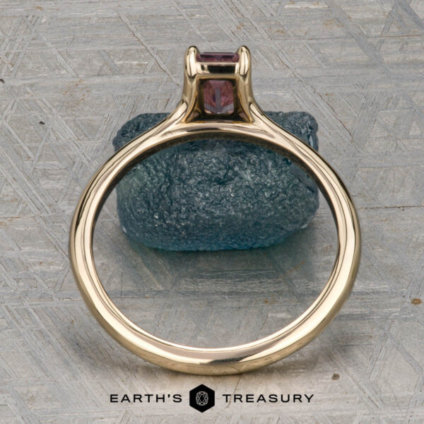 The "Phoebe" ring in 14K yellow gold with 0.73-carat Montana sapphire The "Phoebe" ring in 14K yellow gold, featuring a 0.73-carat Montana sapphire, is displayed on a rough blue stone atop a textured gray surface with the text "Earth's Treasury" below.