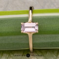 The "Phoebe" ring in 14K yellow gold, featuring a 0.73-carat Montana sapphire, rests on a green surface with the text "EARTH'S TREASURY" at the bottom.