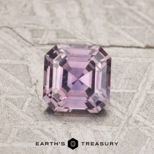 A 0.79-carat Purple Montana Sapphire with a square step cut is shown on a textured background, featuring the "Earth's Treasury" logo below.