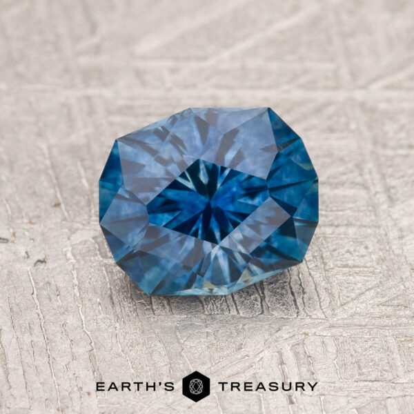 A 1.50-carat Rich Blue Montana Sapphire (Heated) rests elegantly on a white surface, its deep blue hue captivating the eye.