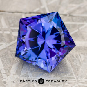 A 3.95-carat Bright Blue Tanzanite (heated), faceted with a geometric star pattern, rests on a textured gray surface. The "Earth's Treasury" logo appears at the bottom.