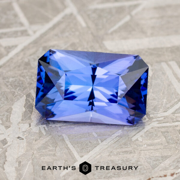 2.08-Carat Medium Blue Tanzanite (Heated) A 2.08-carat medium blue tanzanite with intricate facets, set against a textured gray background. The text "Earth's Treasury" appears at the bottom.