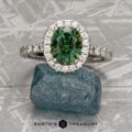 The Classic Pave Halo Ring in 14k white gold with a 1.88-carat Australian sapphire is shown on a rough blue stone, with a diamond-studded band and the Earth's Treasury logo below.