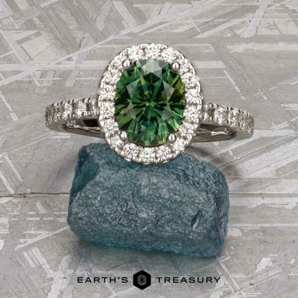 The Classic Pave Halo Ring in 14k white gold with 1.88-Carat Australian Sapphire The Classic Pave Halo Ring in 14k white gold with a 1.88-carat Australian sapphire is shown on a rough blue stone, with a diamond-studded band and the Earth's Treasury logo below.