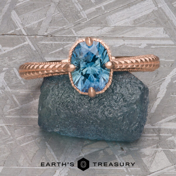 The “Demeter” Ring in 14k rose gold with 1.18-Carat Montana Sapphire A rose gold ring, “2022-01-10 11-08-56 (B,Radius1,Smoothing1)-1200-BW,” with an oval blue gemstone on rough blue stone and the "Earth's Treasury" logo—ideal for Demeter Solitaire fans or lovers of classic solitaire elegance.