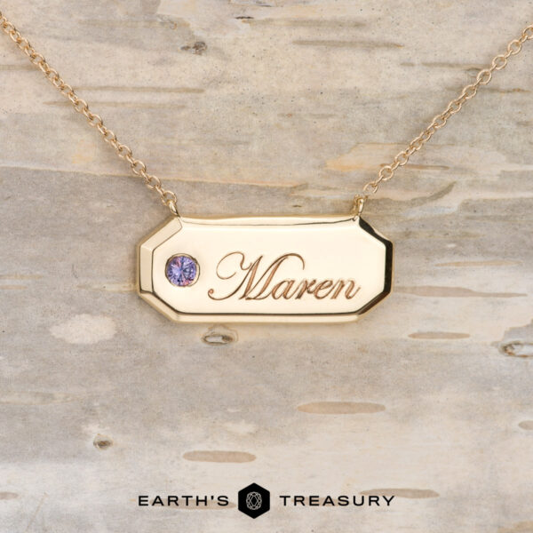 Stacked from 16 images. Method=B (R=1, S=1)" gold keepsake necklace with "Maren" engraved on the pendant and a small gemstone, showcased on light wood. "Earth's Treasury" logo appears at the bottom.