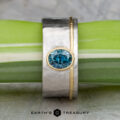 The "Armando" ring features a 1.57-carat round Montana sapphire set in silver and gold, displayed on a green and white stem with the Earth’s Treasury logo below.