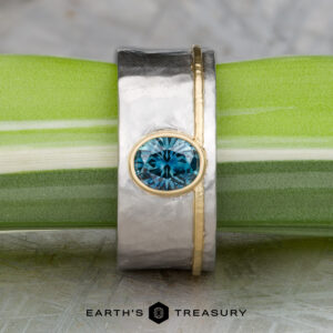 The "Armando" ring features a 1.57-carat round Montana sapphire set in silver and gold, displayed on a green and white stem with the Earth’s Treasury logo below.