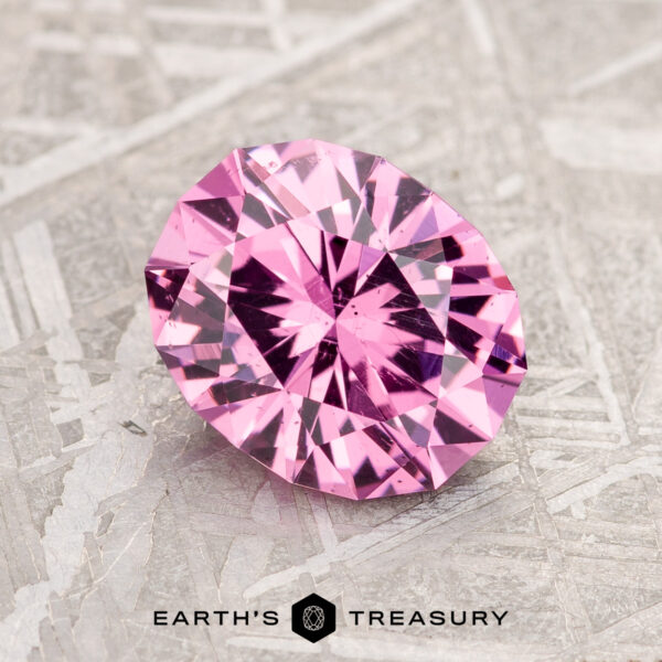 A 2.02-carat Bubblegum Pink Mahenge Garnet displayed on a textured surface with the logo and text "Earth's Treasury" below.