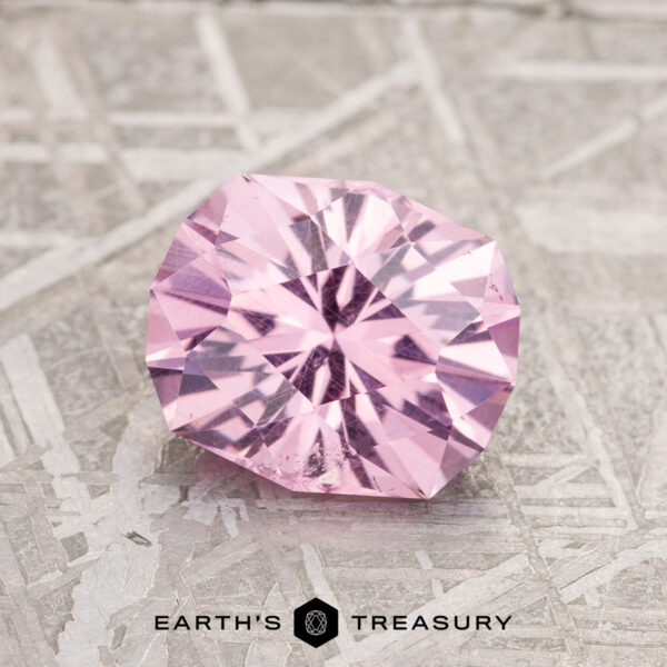 1.87-Carat Lilac Pink Mahenge Garnet A 1.87-carat Lilac Pink Mahenge Garnet is elegantly showcased on a textured gray surface, with the text "Earth's Treasury" appearing at the bottom.