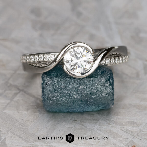 The "Faye" ring in platinum with 0.71-carat lab diamond The "Faye" ring in platinum featuring a 0.71-carat lab diamond rests on a rough blue gemstone, with the "Earth's Treasury" logo shown below.