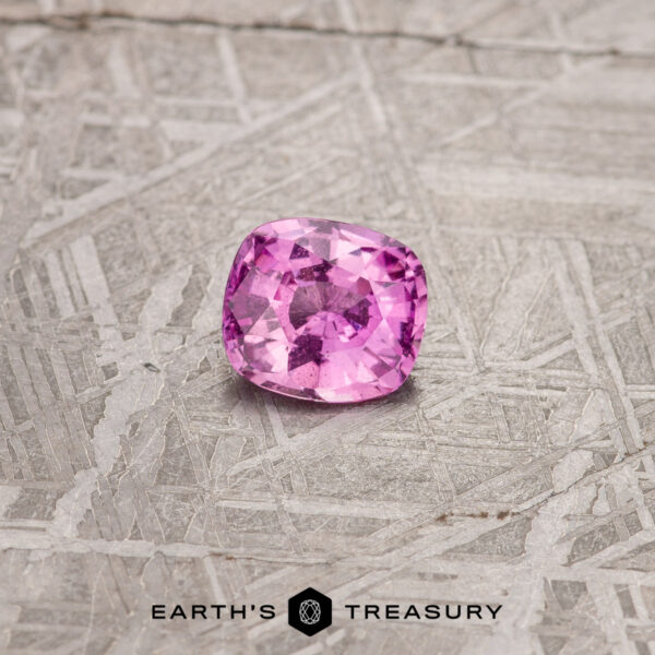 1.08-Carat Hot Pink Madagascar Sapphire The 1.08-Carat Hot Pink Madagascar Sapphire, in a cushion cut, beautifully rests on a textured gray surface.