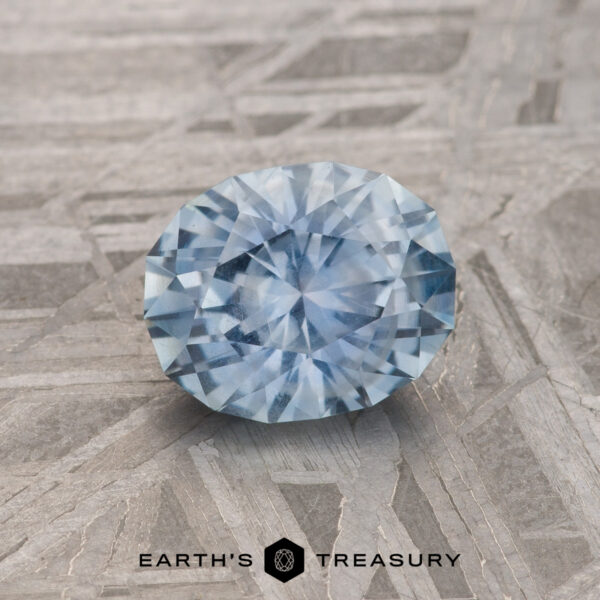 1.23-Carat Sky Blue Montana Sapphire A 1.23-Carat Sky Blue Montana Sapphire is shown on a gray patterned surface with "EARTH'S TREASURY" at the bottom.