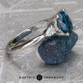 The Minimal "Avalon" ring in 18k white gold with a 1.69-carat Montana sapphire is displayed on a rough blue mineral, with the "Earth's Treasury" logo below.