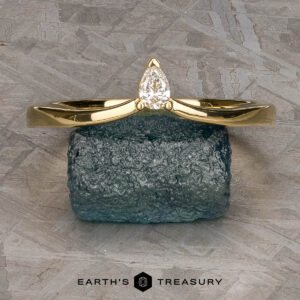 The "Laita" band in 18K yellow gold is showcased elegantly on top of a rock.