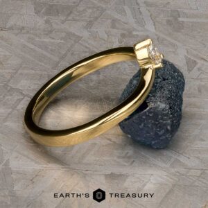 The "Laita" band in 18K yellow gold is showcased elegantly on top of a rock.