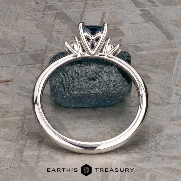 The "Alocasia" ring in 18K white gold with 1.00-carat Montana sapphire The "Alocasia" ring in 18K white gold features a 1.00-carat rectangular Montana sapphire and two round diamonds, shown atop a rough blue crystal with the "Earth's Treasury" logo below.