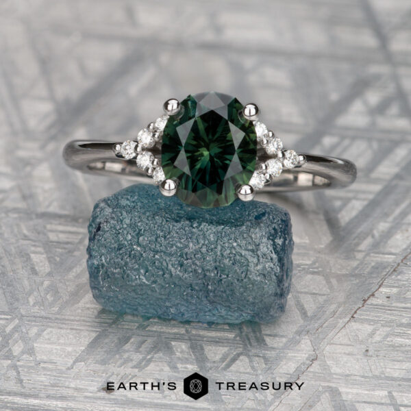 The "Chiron" ring in 14K white gold with 2.25-carat Australian sapphire The "Chiron" ring in 14K white gold, featuring a 2.25-carat Australian sapphire, is displayed on rough blue Chiron crystal with the "Earth's Treasury" logo beneath.