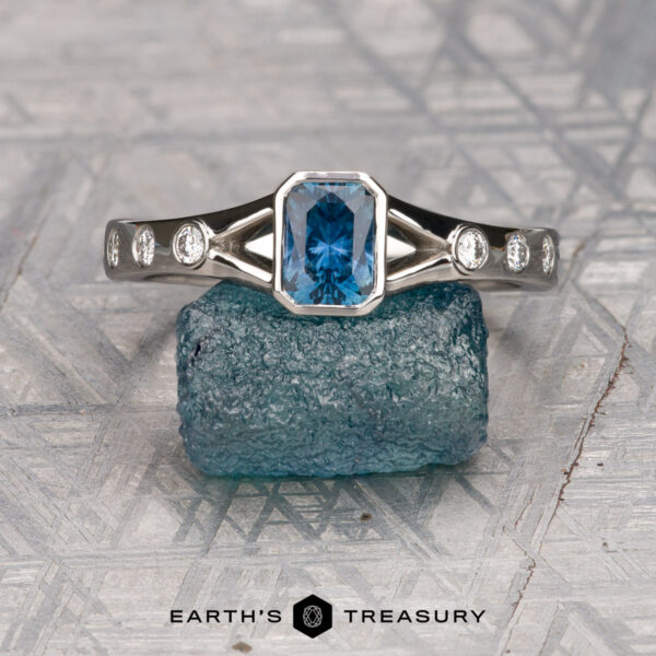 The "Corvus" ring in platinum with 0.74-carat Montana sapphire The "Corvus" ring in platinum with a 0.74-carat Montana sapphire is displayed on a rough blue stone, small diamonds accenting the rectangular blue gem, with the "Earth's Treasury" logo below.